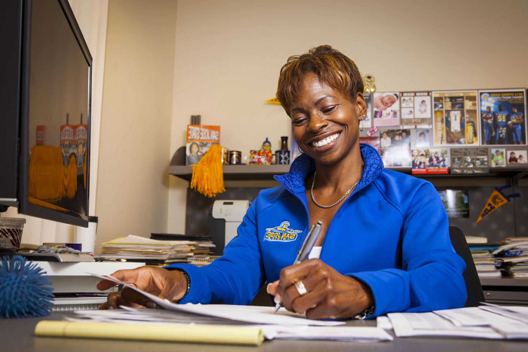 Coleetta McElroy smiling while doing paperwork.