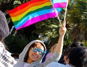 A student waiving a Rainbow-Colored Flag.