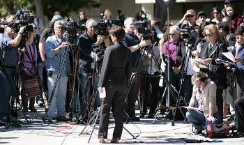 一个人站在外面准备发表声明周围有一堆摄像机和记者